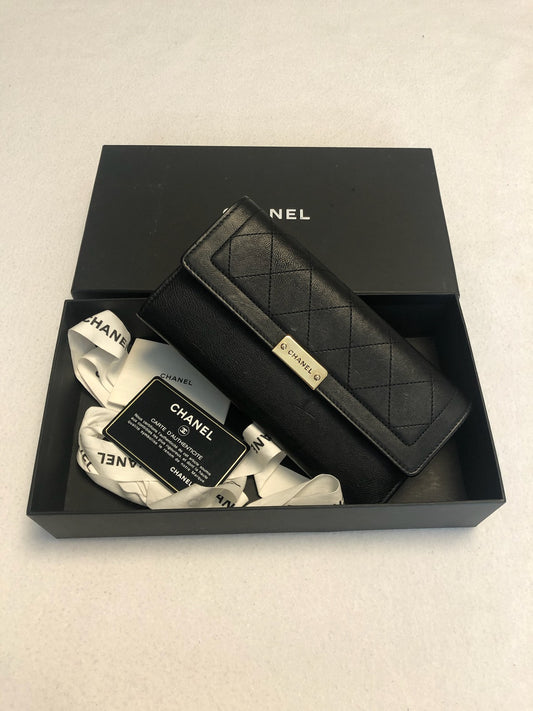Chanel black flap wallet pictured in a box with ribbon and cards