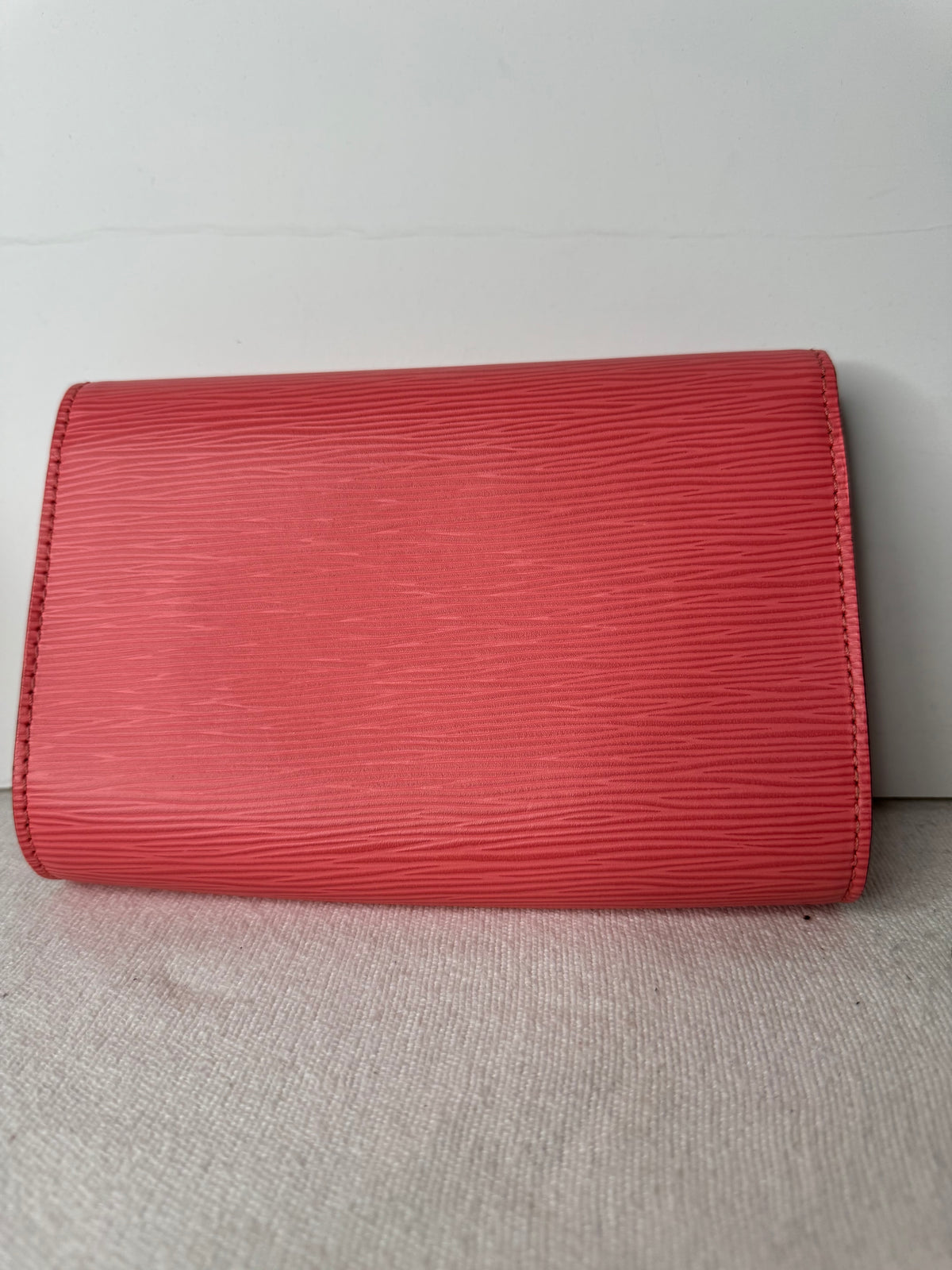 Back of coral-pink Louis Vuitton textured wallet