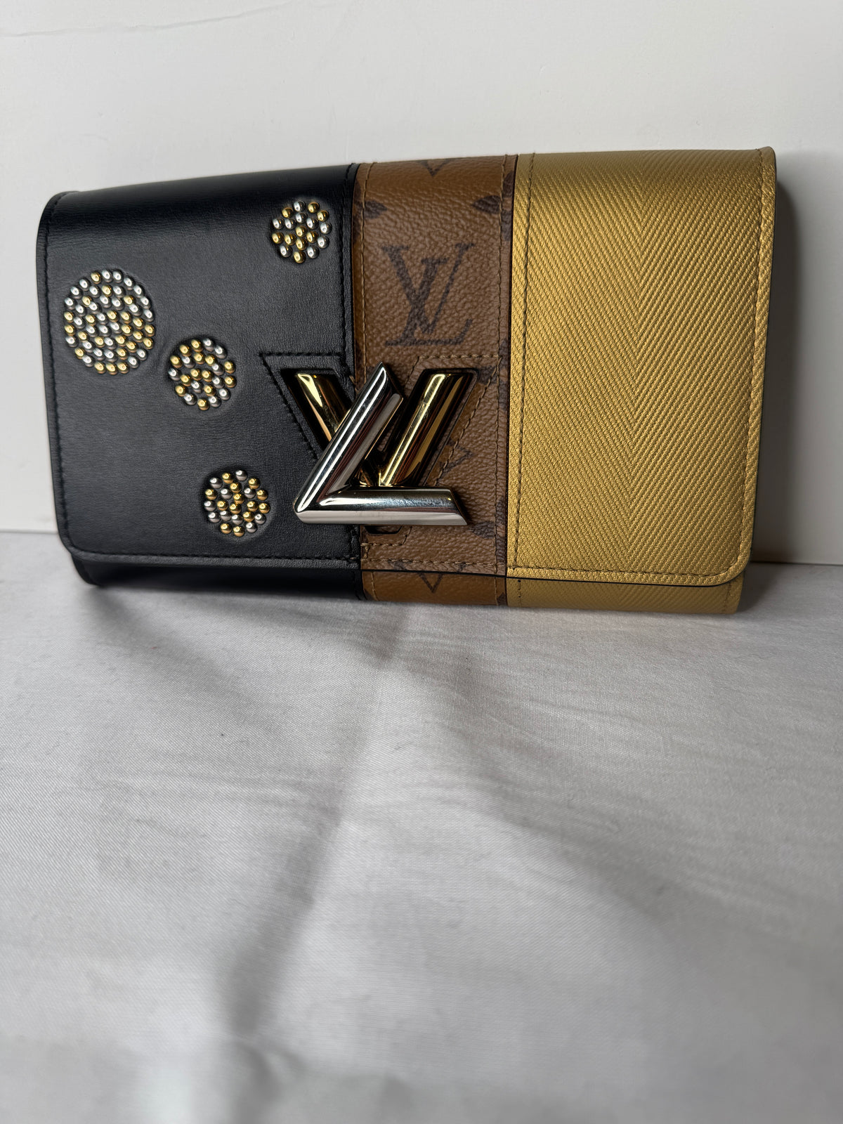 Back of Louis Vuitton clutch with gold-tone, brown monogram, and black panels