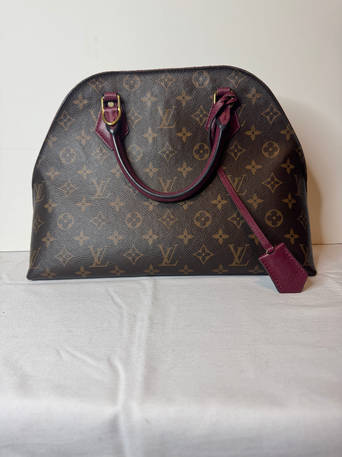 Opposite exterior view of Louis Vuitton monogram top handle bag with burgundy trim