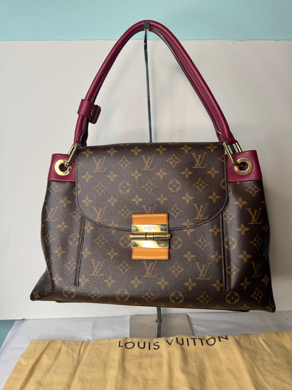 Front view of Louis Vuitton brown monogram shoulder bag with burgundy strap and gold-tone clasp