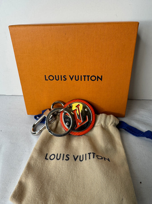 Louis Vuitton circular LV keychain with orange accents, silver-tone key ring and clasp, pictured with a box and dust pouch