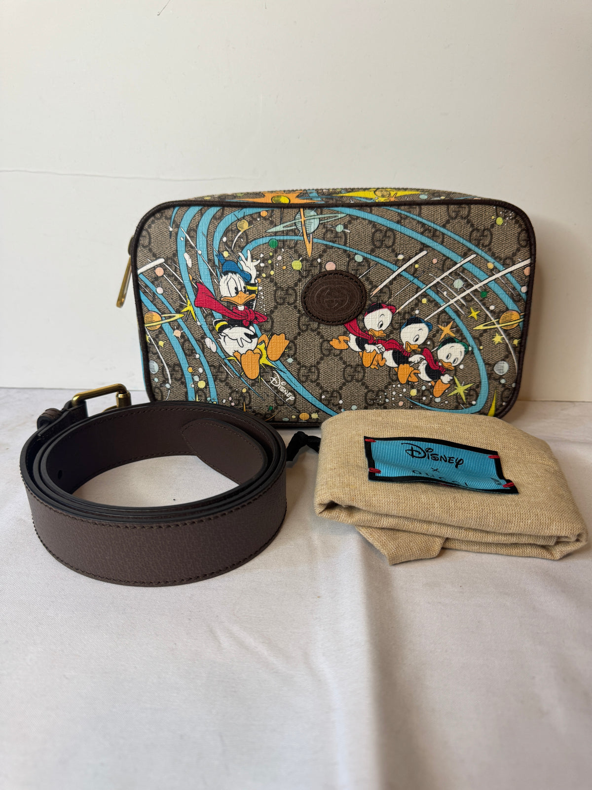 Gucci Disney Donald Duck GG print belt bag pictured with a brown belt and Disney dust bag