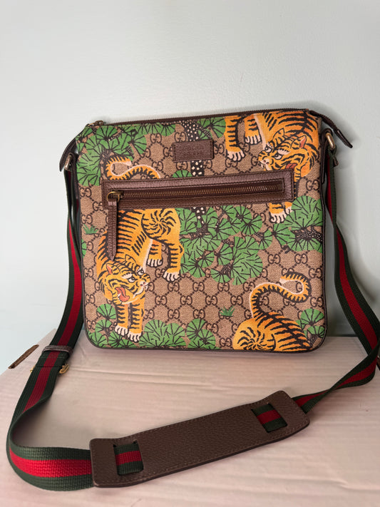Gucci GG monogram messenger bag with orange tiger and green foliage print, brown trim, and green-and-red striped strap