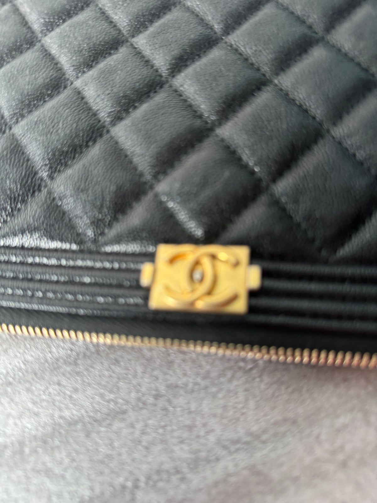 Front view of black quilted Chanel zip clutch with gold-tone CC detail